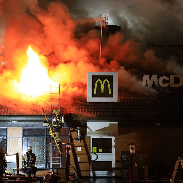 Brandmän bekämpar brand på McDonalds-restaurang. Eld slår upp genom taket.