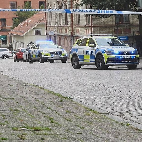 Två polisbilar med blåljus parkerade på en gata i Borås.