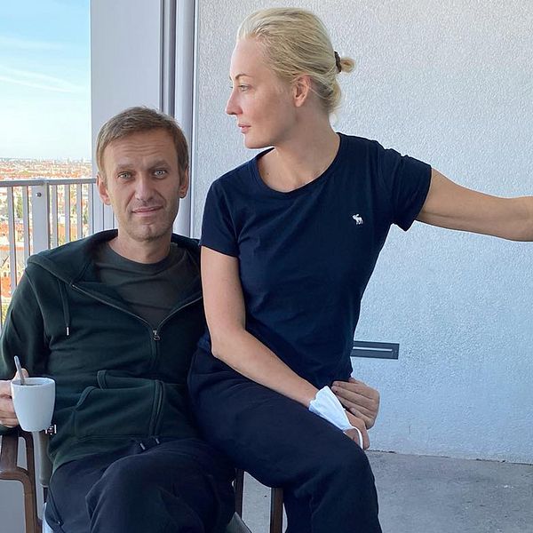 Aleksej Navalnyj med en kaffekopp i handen tillsammans med frun Yulia på en balkong.