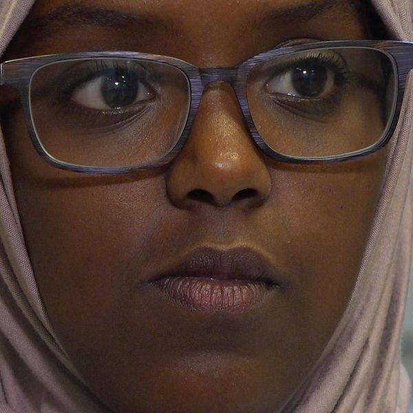 nära bild på en ung mörkhyad kvinna med glasögon och sjal