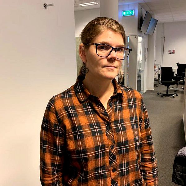 en kvinna med rutig skjorta och brunt hår och glasögon poserar i TV-huset i Falun.
