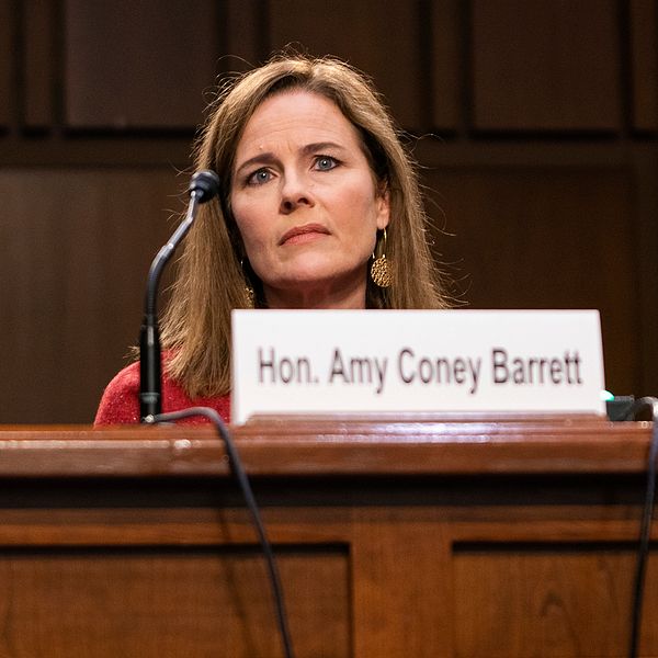 Bild tagen underifrån. Domarkandidaten Amy Coney Barrett sitter framför sin mikrofon i USA:s senat.