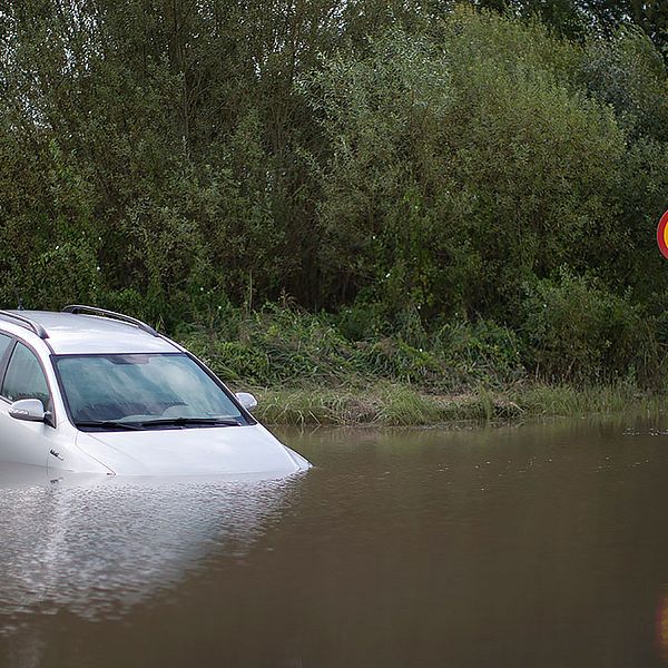 En bil halvvägs täckt av vattenmassor i Getinge, Halland förra sommaren.