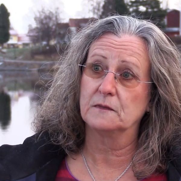 En kvinna med tonade glasögon intervjuas vid ett vattendrag