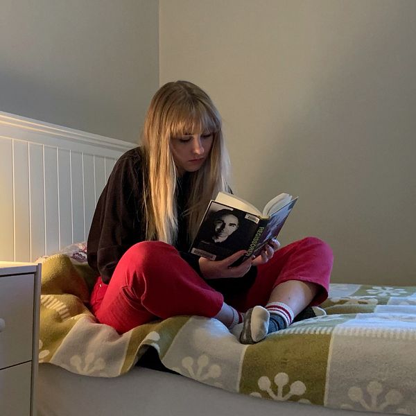 Vilhelmina, en tonårig tjej, sitter på sin säng och läser en bok