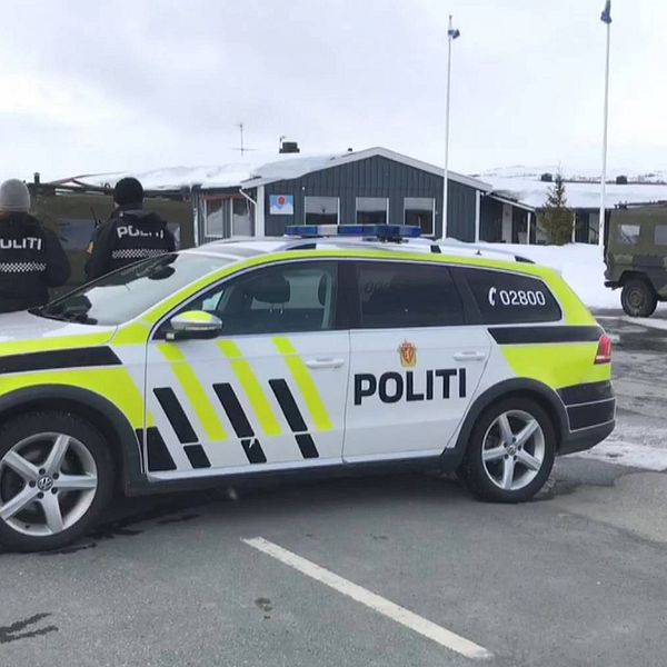 Bild på norsk polisbil på en väg. Två poliser står vid bilen.