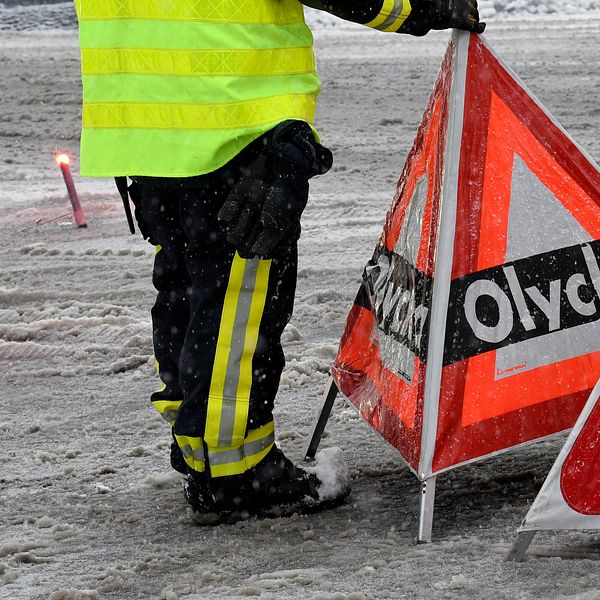 Bilden visar när personal från räddningstjänsten varnar med skylt om en olycka på vägen.