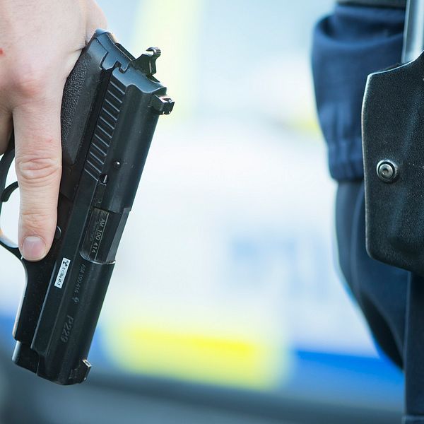 Hand som håller i en pistol, polisens tjänstevapen.