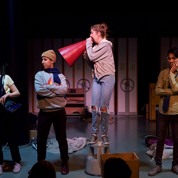 Fyra stycken ungdomar står på en scen och spelar teater.