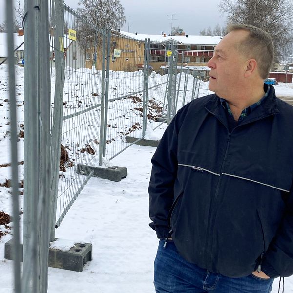 Magnus Hedni står bakom ett stängsel och blickar ut över platsen där hans gamla matbutik låg i Järvsö.