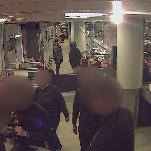 Övervakningsbild som visar butikspersonal som konfronterar en person som försökt stjäla en salami i mataffären. De står efter kassorna och en från butiken har tagit tag i kragen på tjuven. De inblandade personerna är anonymiserade.