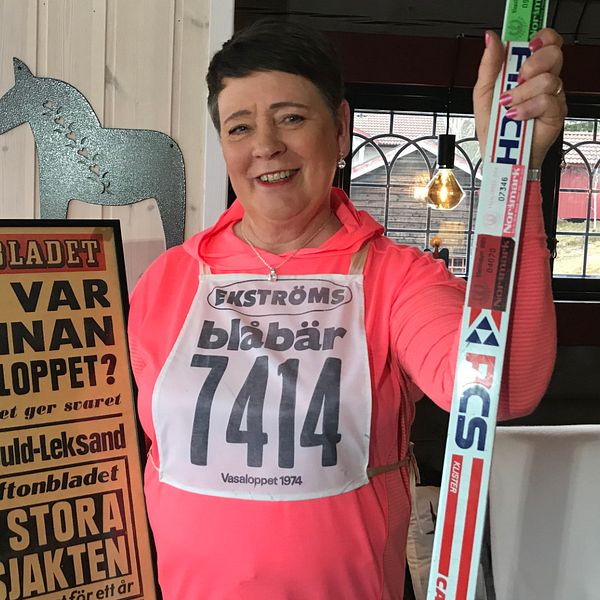 Medelålders kvinna som håller upp löpsida från aftonbladet och ett par skidor