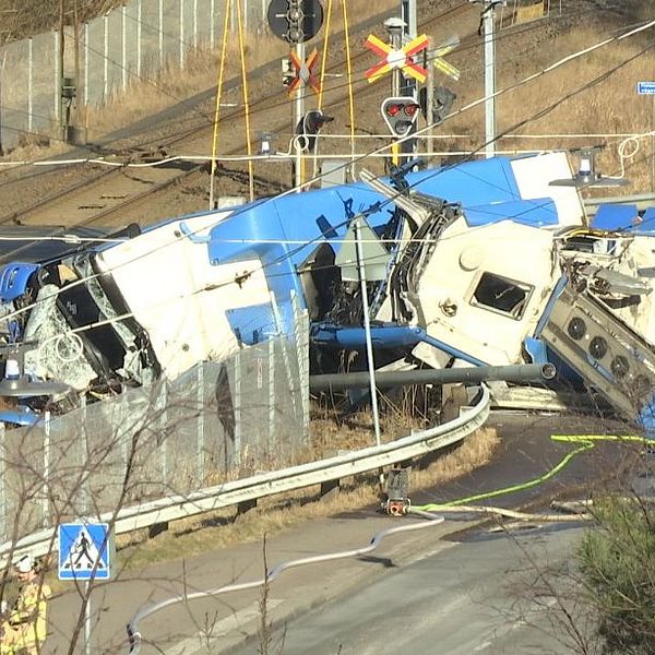 Mycket illa kvaddad buss ligger på järnvägsspåret.