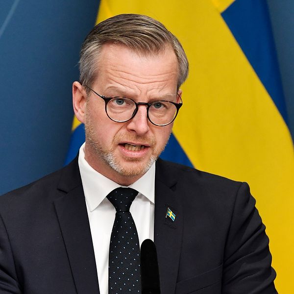 Bilden visar Inrikesminister Mikael Damberg (S) under en av regeringens presskonferenser. I bakgrunden syns svenska flaggan.