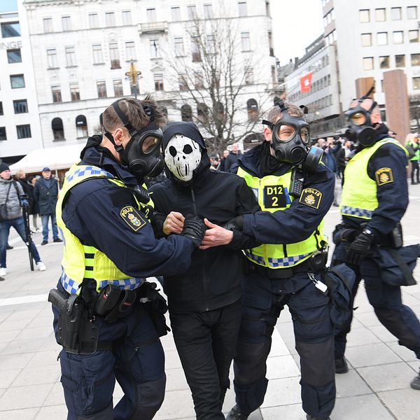 poliser i gasmasker bär bort en demonstrant i mask vid Norrmalmstorg efter en corona-protest