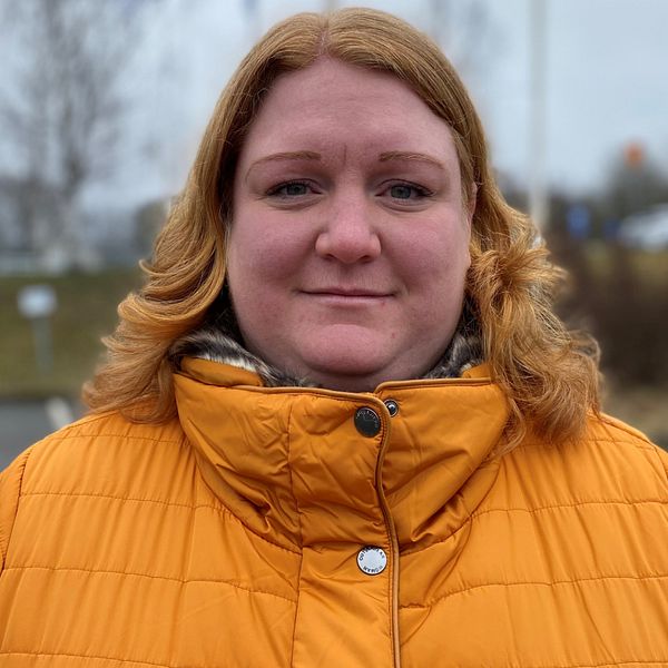 Hanna Sjöholm står utomhus i en gul jacka.