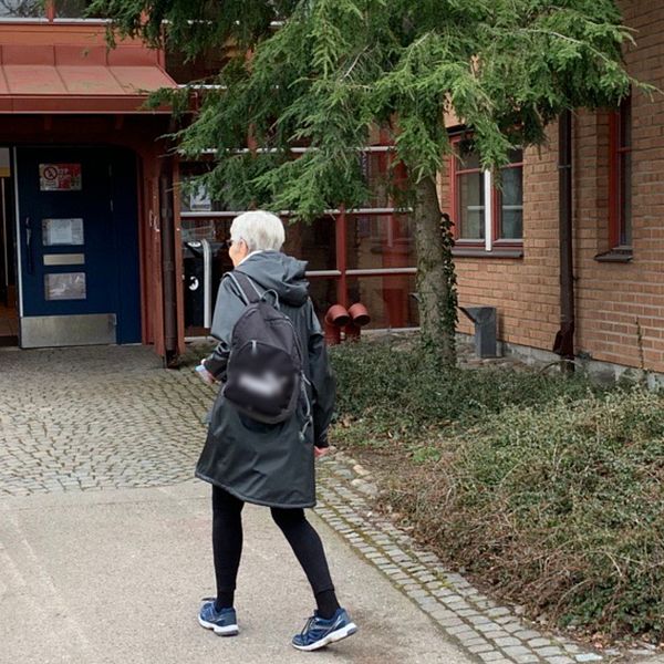 En äldre kvinna är på väg in i Kalmars vaccinationscentral. Utanför möts hon av en annan kvinna som arbetar som funktionär. Hon har skyddsutrustning och reflexväst.