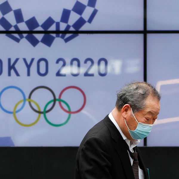 En förbipasserande man framför en av Tokyos OS-skärmar