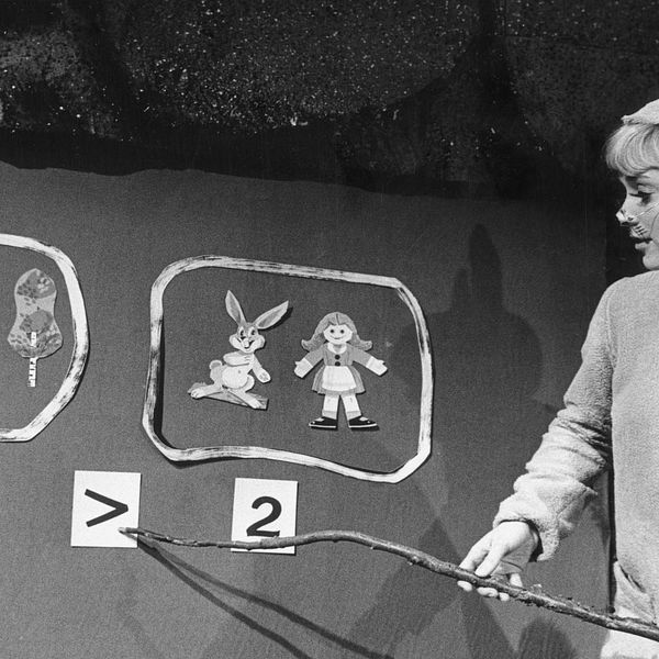 Skådespelaren Britta Pettersson utklädd till hare pekar på en flanellograf.