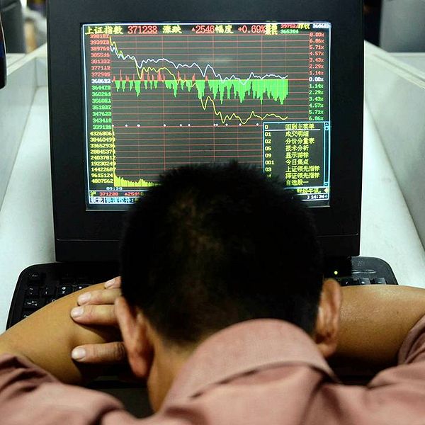 En handlare på Shanghaibörsen sjunker ihop framför sin skärm när kurserna bara faller. Bilden är från den 6 juli – i dag har kurserna dykt ännu mer. Shanghaibörsen föll nästan 7 procent vid öppnandet.