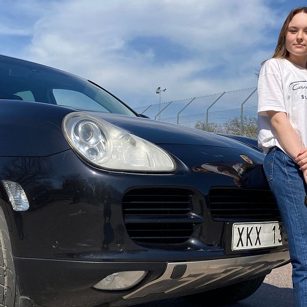 En ung tjej i 15-årsåldern står och lutar sig mot motorhuven på sin Porsche Cayenne som är ombyggd till en A-traktor.