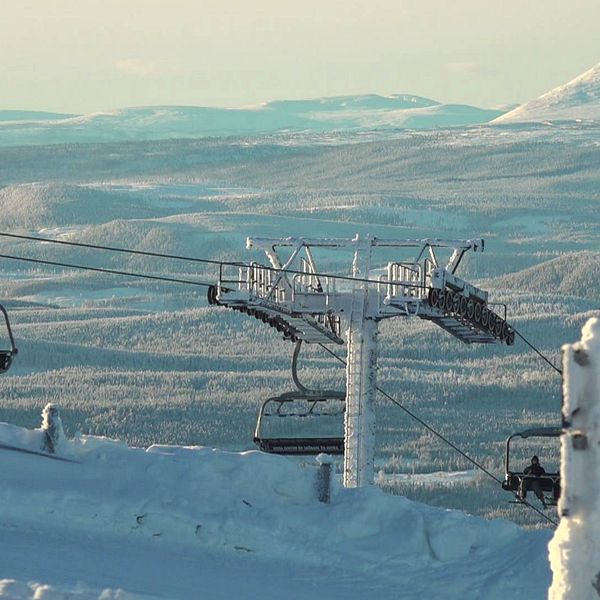 Vinterbild på skidlift med skidåkare i. I bakgrunden fjällmassiv.