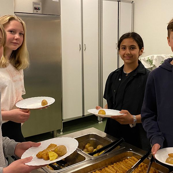 Fyra skolelever som plockar mat i en skolmatsal