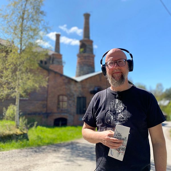 en man med hörlurar framför hyttan i Jädraås – en gammal tegelbyggnad med torn – solig sommardag