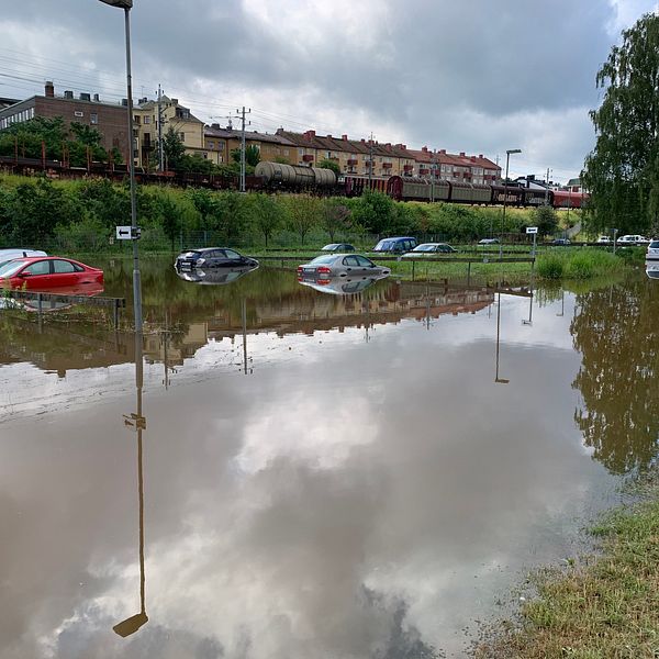 Bilar på en parkeringsplats, bilarna står i meterhögt vatten så går ända upp till rutorna.