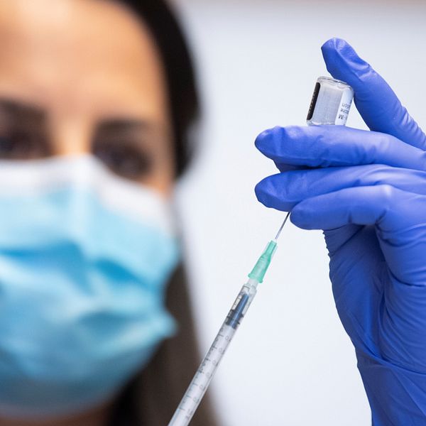 En kvinna fyller på en spruta med vaccin.