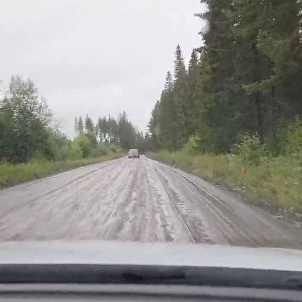 Bil färdas på dålig grusväg i regn.