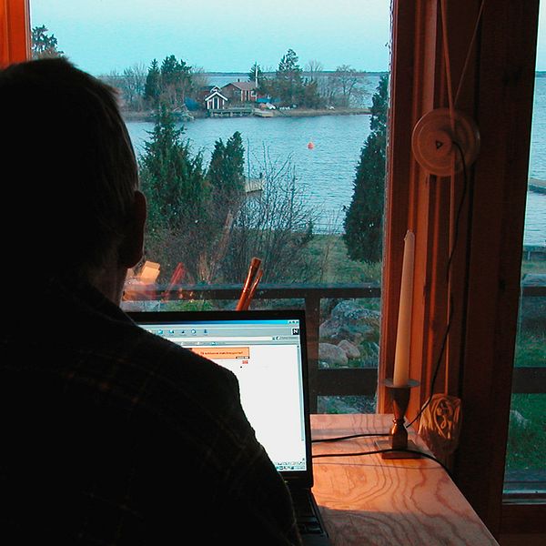 En man jobbar vid sin dator framför ett fönster.