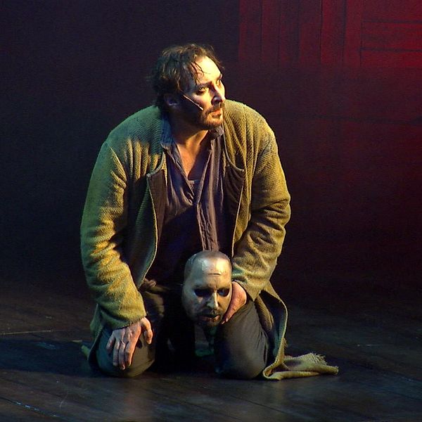 Skådespelaren Jakob Hultcrantz sitter på scen med en ansiktsmask i handen ur föreställningen Körkarlen