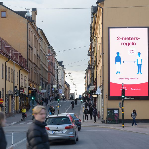 En stor skylt i centrala Stockholm uppmanar folk att hålla 2 meters avstånd.