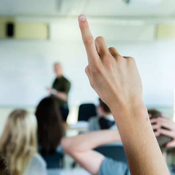 Elever räcker upp handen i ett klassrum
