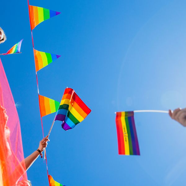 En bild på Pride-flaggor som sträcks mot himlen.