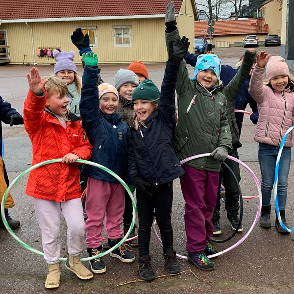 Glada skolbarn med rockringar på skolgården