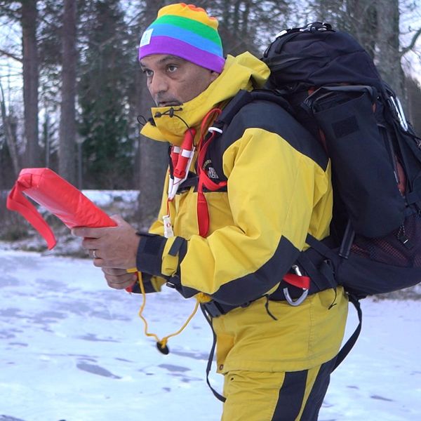 Man med ryggsäck och isdubbar står på isen för att lära ut issäkerhet.