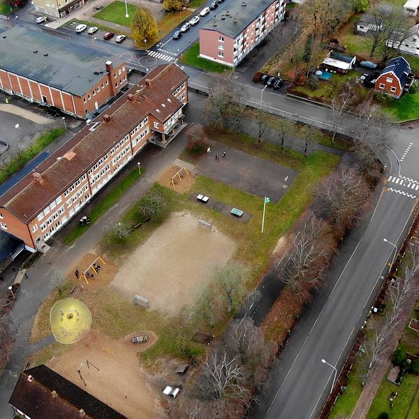 Luftfoto över en skolgård med omgivande byggnader och vägar.