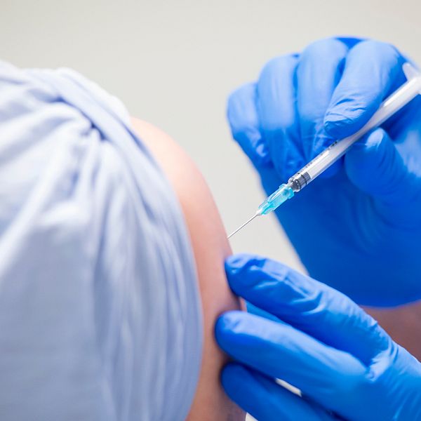 En vaccinatör ger en man en dos vaccin.