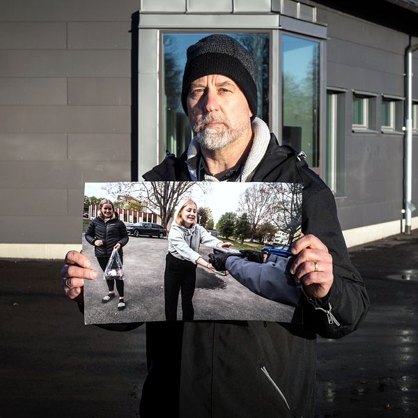 Man i mössa och skägg håller upp bild på flicka som tar emot något.