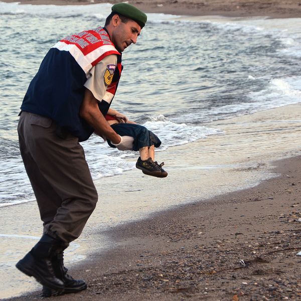 En turkisk militärpolis bär bort den döda pojken.