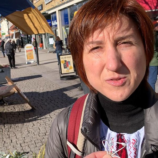 Människor på torget, klädda i vinterkläder, delvis skuggade av marknadsstånd.