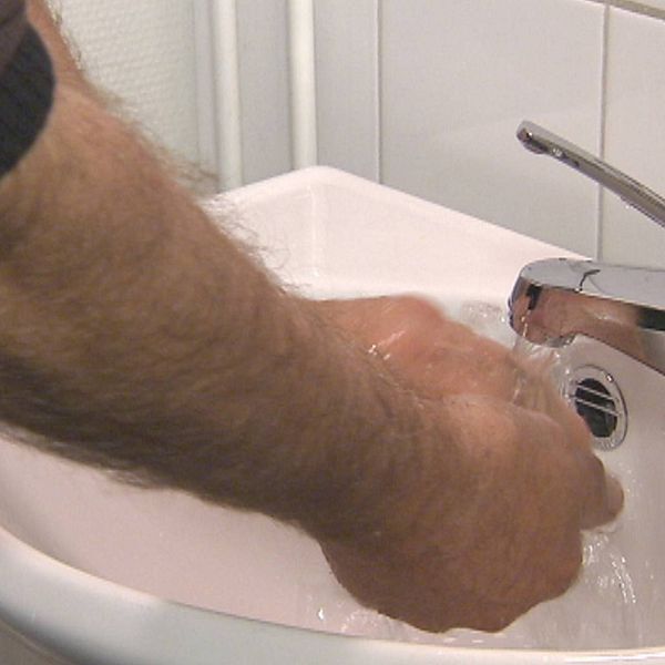 Ett vitt handfat där någon tvättar sina händer.