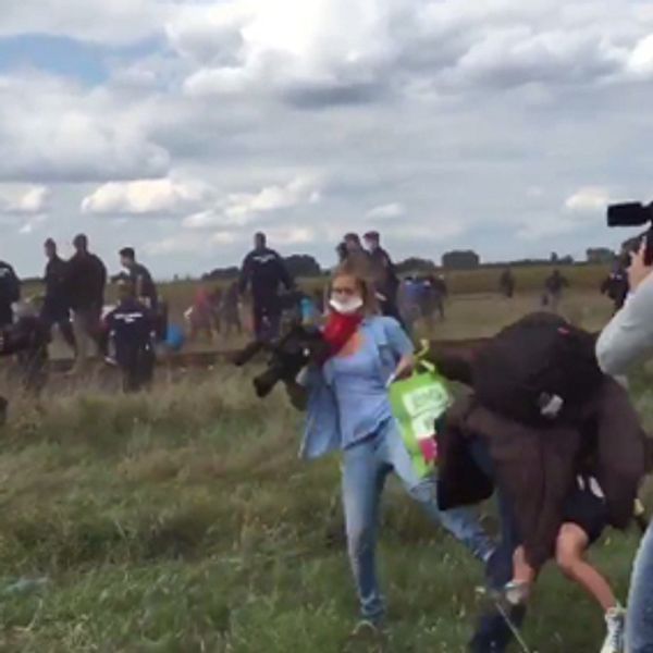 En ungersk journalist fäller krokben för en flyende man på ett fält utanför staden Röszke.