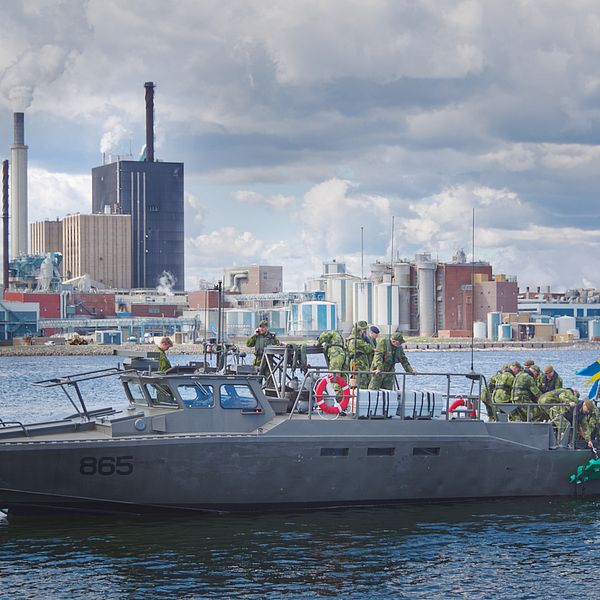 Stridsbåt 90 med soldater som lägger hamnminor i Skutskär. Fabriken syns i bakgrunden.