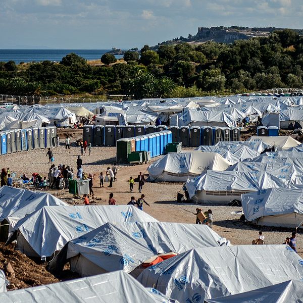 Tiotals vita tält och utomhustoaletter på en stor grusplan på den grekiska ön Lesbos.