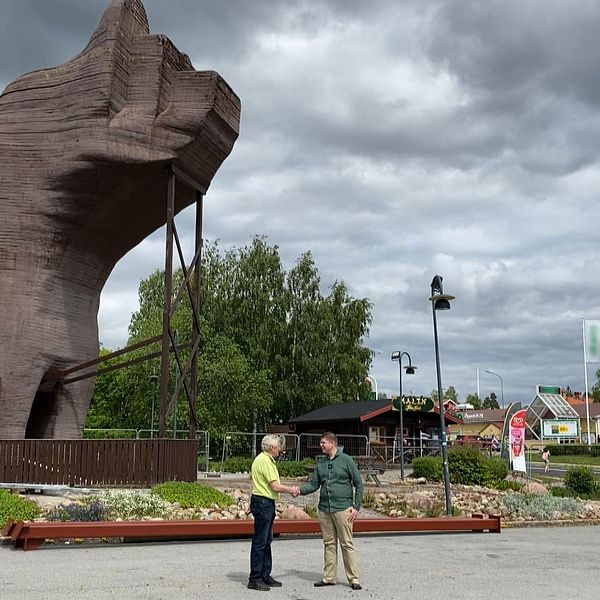 Kommunen lämnar över björnen till Svegs företagarförening – två män skakar hand framför den stora träbjörnen