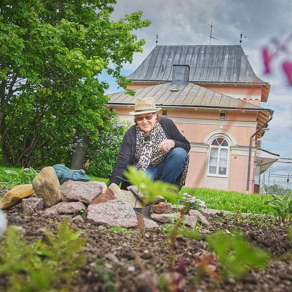 Marit Snaar planterar en blomma i trädgården vid stationshuset i Storvik.