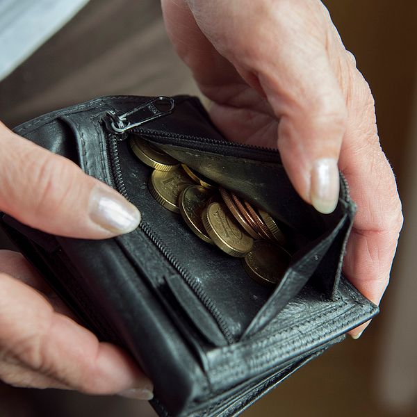 Händer som håller i en plånbok med mynt i.